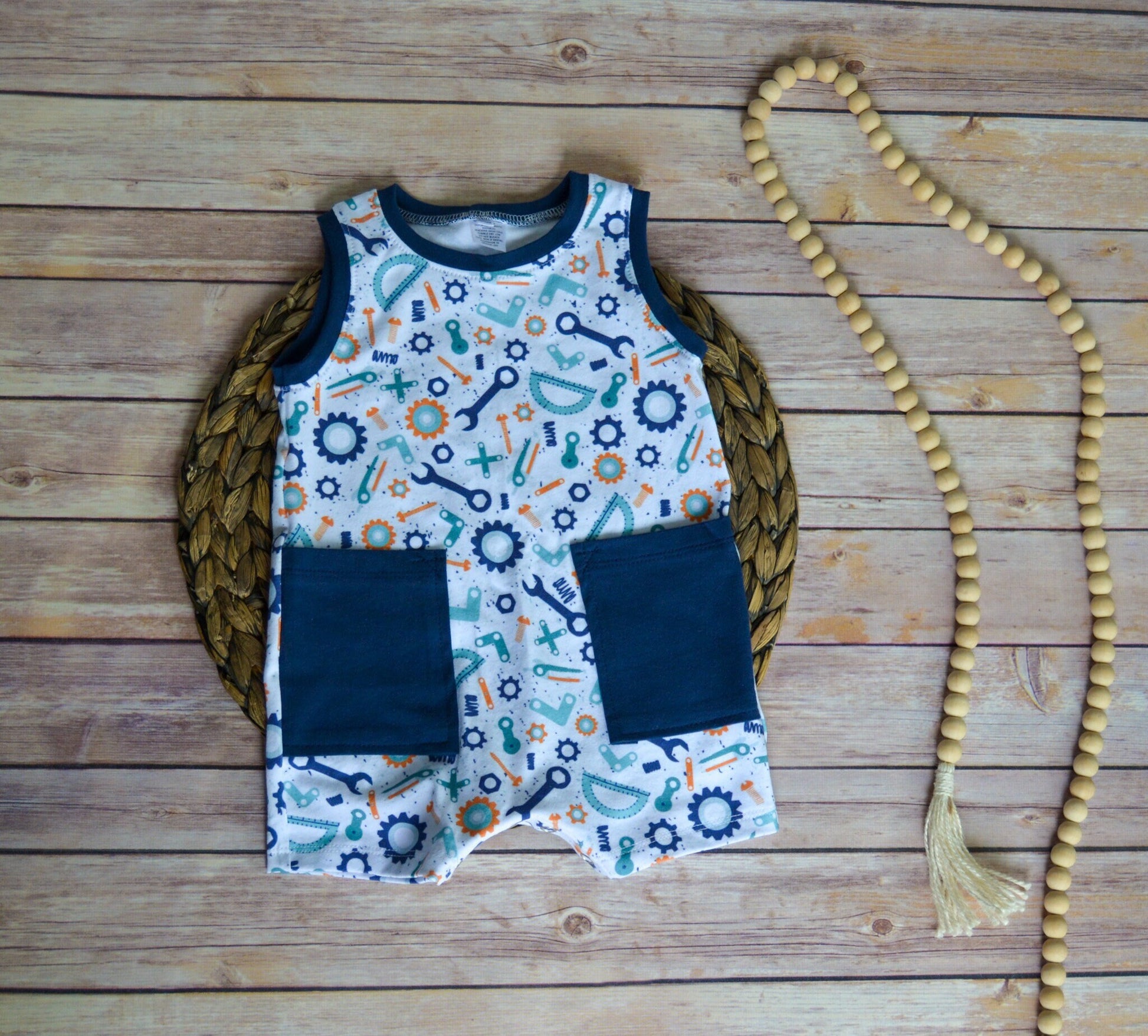 Children's sleeveless shirt with tool pattern and navy pocket on a wooden surface